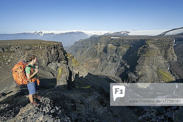 Wanderer blickt in die Ferne  Canyon aus Vulkanstein  hinten Gletscher Myrdalsjökull  vulkanische Landschaft am Wanderweg Fimmvörðuháls  Þórsmörk Nature Reserve  Suðurland  Island  Europa