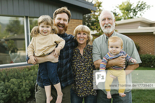 Portrait of smiling three generation family with children (2-3  4-5) in back yard