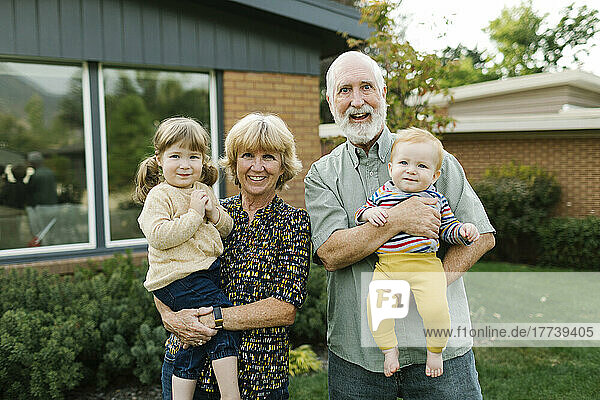 Portrait of smiling grandparents with grandchildren (2-3  4-5) in back yard