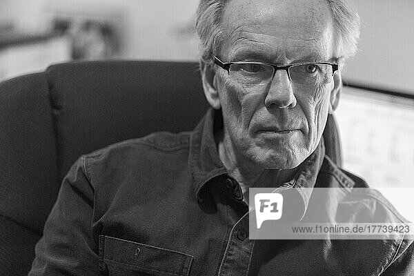 Portrait of senior man with laptop in background  black and white