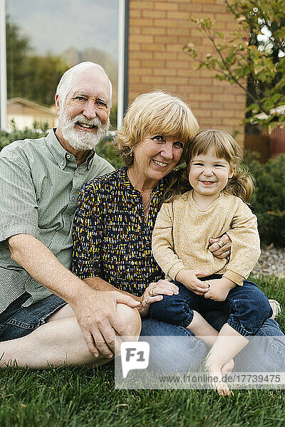 Portrait of smiling grandparents with granddaughter (4-5) on back yard