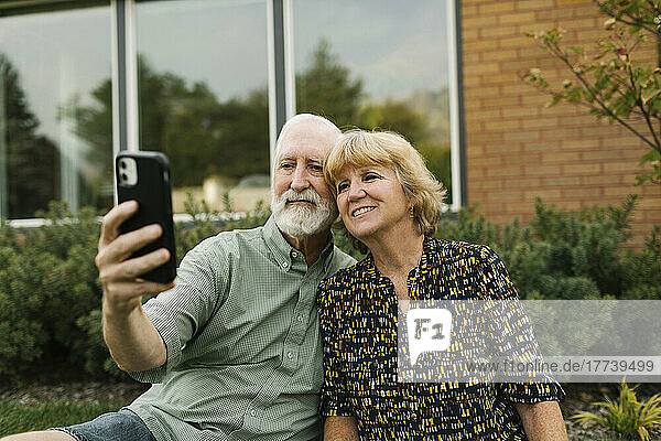Smiling senior couple taking selfie in backyard