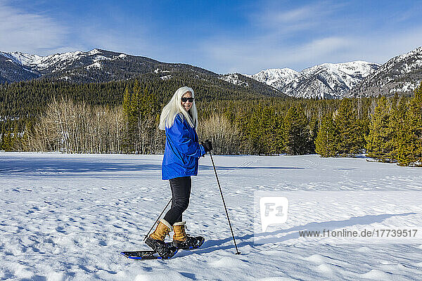 USA  Idaho  Ketchum  Portrait of senior blonde woman snowshoeing in snow covered landscape