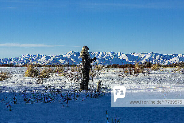 USA  Idaho  Bellevue  Senior blonde woman snow shoeing in snow covered landscape