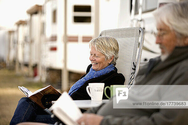 Senior couple reading book outside mobile home