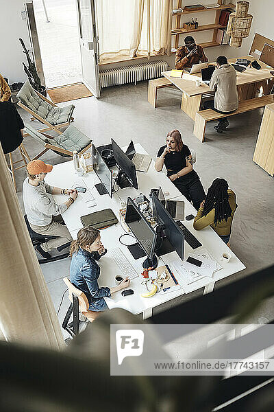 Blick von oben auf die Kollegen eines Startup-Unternehmens  die im Büro zusammenarbeiten