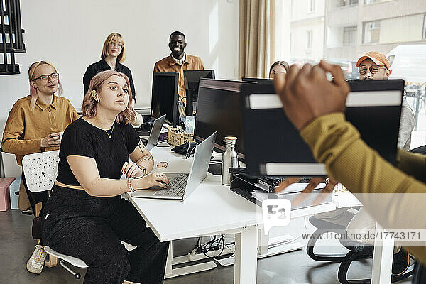 Startup-Kollegen sitzen am Schreibtisch und hören einer Geschäftsfrau zu  die bei einer Besprechung im Büro ihre Strategie erläutert
