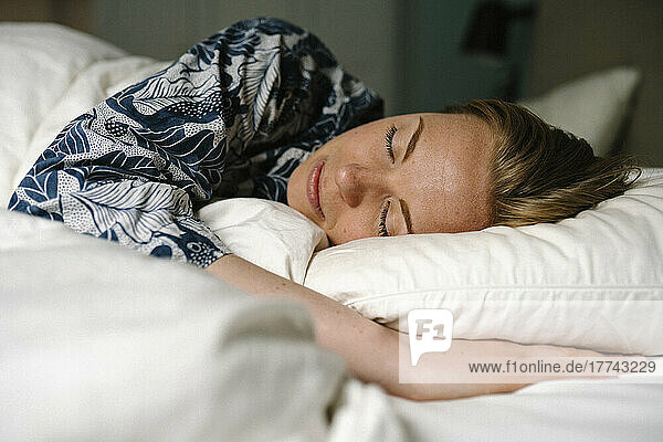 Woman sleeping on bed in bedroom at home