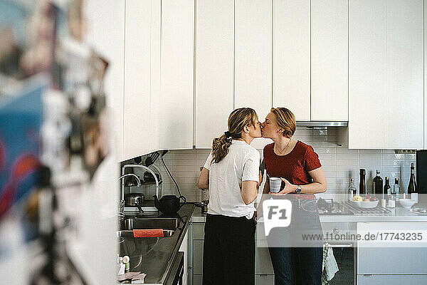Zärtliches lesbisches Paar küsst sich in der Küche zu Hause