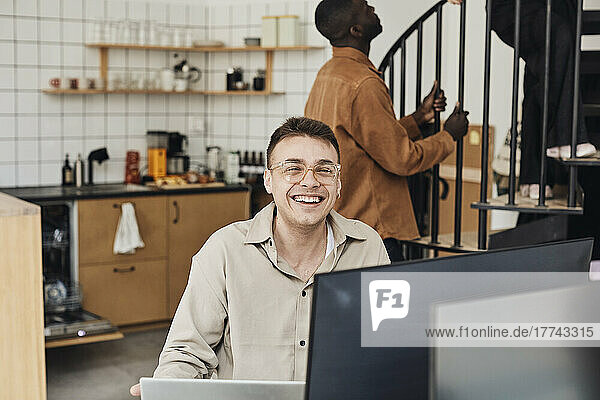 Portrait of happy male computer programmer sitting in office