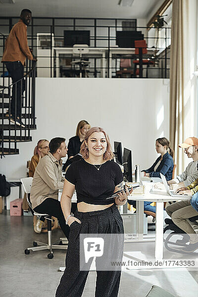 Porträt einer jungen Geschäftsfrau mit Hand in der Tasche  die in einem Büro eines Technologie-Start-ups steht