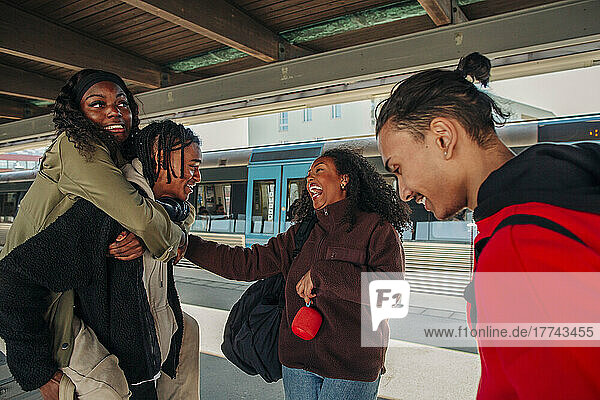 Junge Frau lacht  während sie auf spielerische Freunde am Bahnhof schaut