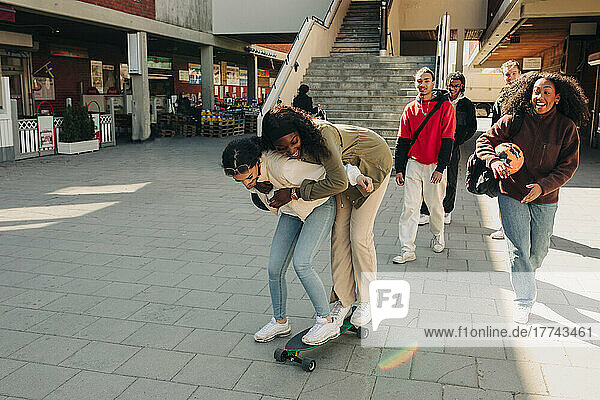 Verspielte Freundinnen stehen auf einem Skateboard auf der Straße