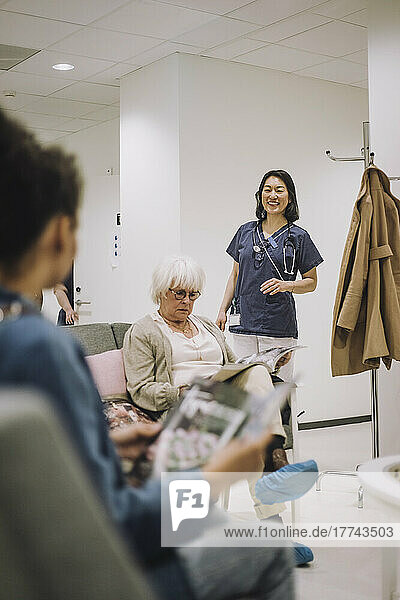 Lächelnde Ärztin betrachtet weibliche Patienten im Wartezimmer eines Krankenhauses