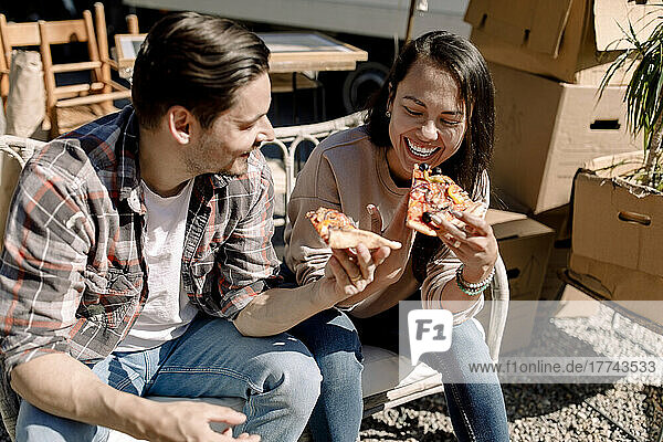 Cheerful couple eating pizza while relocating to new home