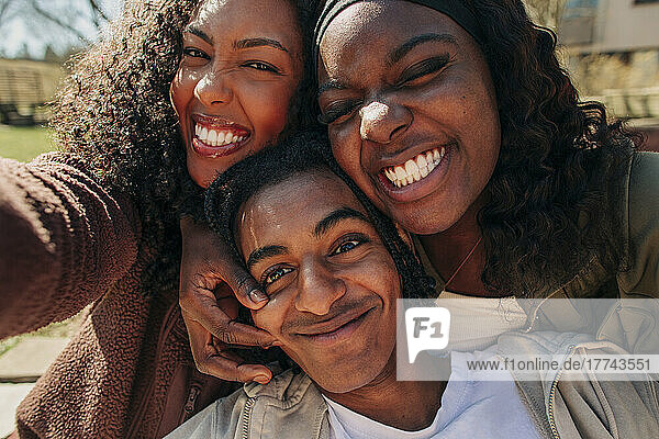 Glückliche junge Freunde machen Gesichter  während sie zusammen ein Selfie machen