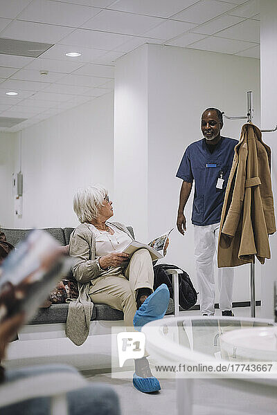Lächelnder Arzt im Gespräch mit einer älteren Frau im Wartezimmer