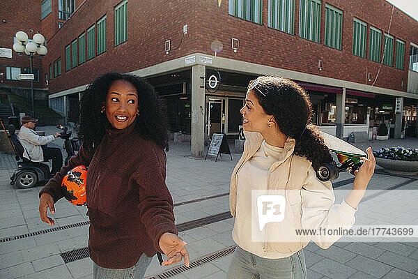 Junge Frau im Gespräch mit einer Freundin beim Gehen auf der Straße
