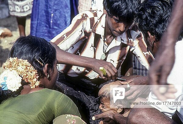 Indian Hindu devotees tonsuring or shaveing their baby head as an offering during Chitra or Chithirai festival in Madurai Tamil Nadu  India  Asia