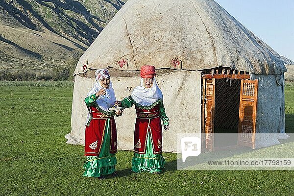 Two Kazakh woman in traditional dress in front of a yurt greeting guests with sweets  For editorial use only  Sati village  Tien Shan Mountains  Kazakhstan  Asia