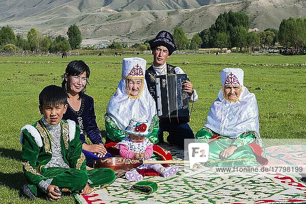 Kasachische Familie in traditioneller Kleidung  die der Musik eines Akkordeonspielers lauscht  Nur für den redaktionellen Gebrauch  Dorf Sati  Tien-Shan-Gebirge  Kasachstan  Asien