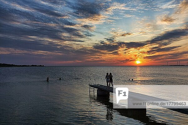 Two people  silhouettes on bathing jetty by the sea  evening sky at sunset  backlight  Baltic Sea  Burgsvik  Gotland Island  Sweden  Europe