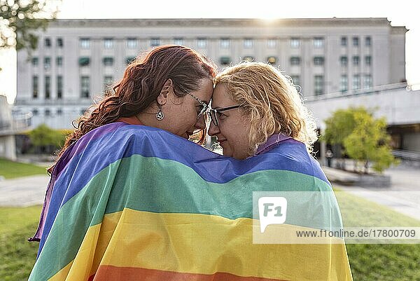 Lesbian couple under LGBT rainbow flag while looking at each other. Concept of Pride. Pride month