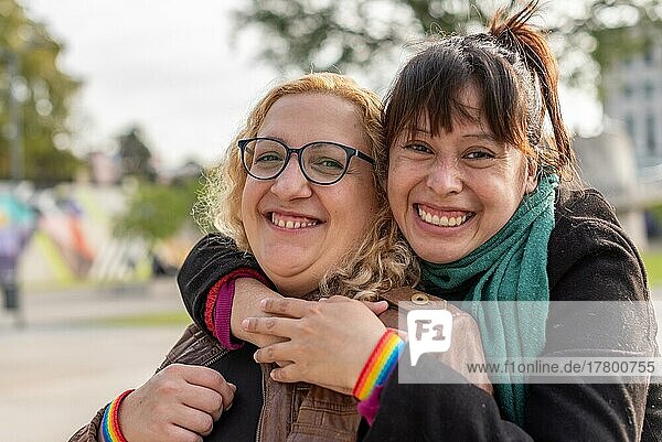 Portrait of a smiling lesbian couple hugging each other while standing together outdoors  looking at camera