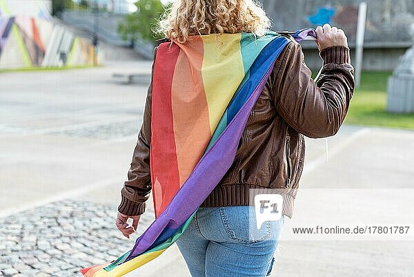 Back view of a lesbian activist on under LGBT rainbow flag. Concept of Pride. Pride month
