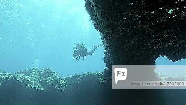 Female scuba diver swim near the exit from the cave. Cave diving in Mediterranean Sea  Cyprus  Europe