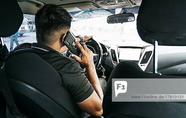 Man driver calling on the phone in his car  Back view of a young man sitting inside car using mobile phone  concept of man calling on the phone while driving