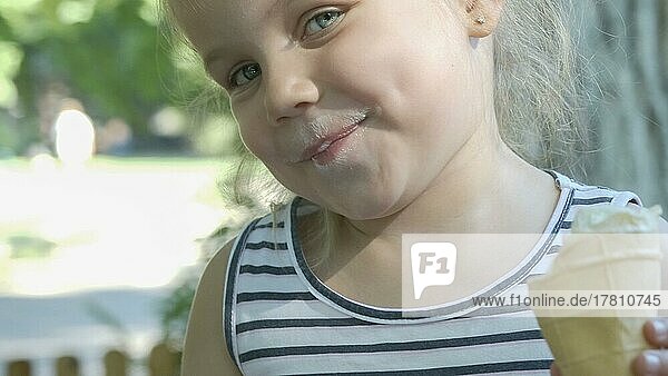 Süßes kleines Mädchen isst draußen Eis. Close-up-Porträt von blonden Mädchen sitzen auf Parkbank und essen Eis. Odessa Ukraine