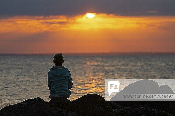 Woman sitting on stones  sunset  Steinbeck  Klütz  Mecklenburg-Western Pomerania  Germany  Europe