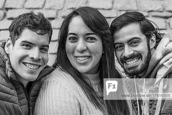 Porträt von drei glücklichen Freunden in Schwarz Weiß. Sie schauen in die Kamera
