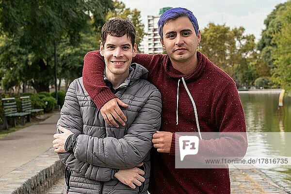Homosexuelles männliches Paar  das sich umarmt und in die Kamera schaut  im Freien
