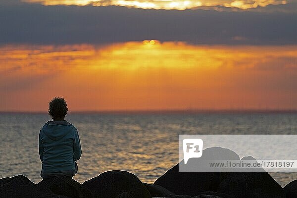 Woman sitting on stones  sunset  Steinbeck  Klütz  Mecklenburg-Western Pomerania  Germany  Europe