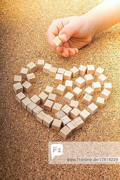 Kleine Holzwürfel in Herzform oder Valentinstagssymbol und Hand