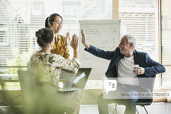 Happy business colleagues giving high-five to each other in office