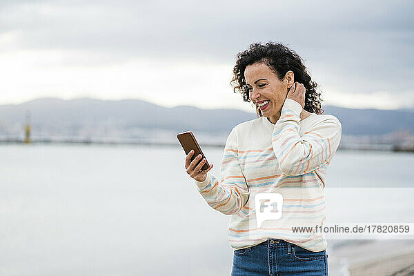 Happy woman using phone at beach on weekend