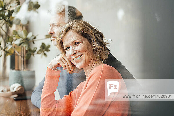 Lächelnde Frau  die vor einem Mann im Café sitzt und durch Glas gesehen wird