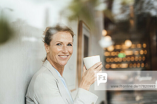 Happy businesswoman holding coffee cup in cafe