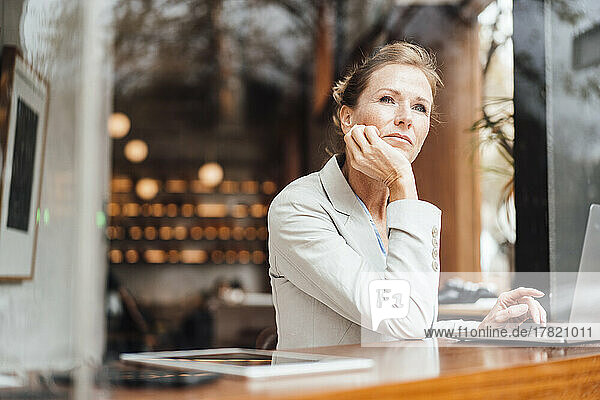 Thoughtful businesswoman with head in hands at cafe