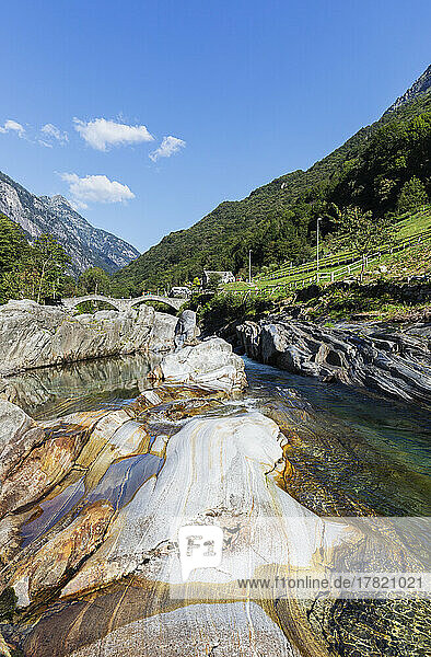 Switzerland  Ticino  Lavertezzo  Verzasca river flowing through Valle Verzasca in summer with Ponte dei Salti arch bridge in background