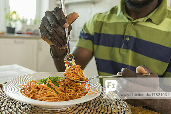 Hände eines Mannes  der zu Hause eine Gabel mit Spaghetti hält