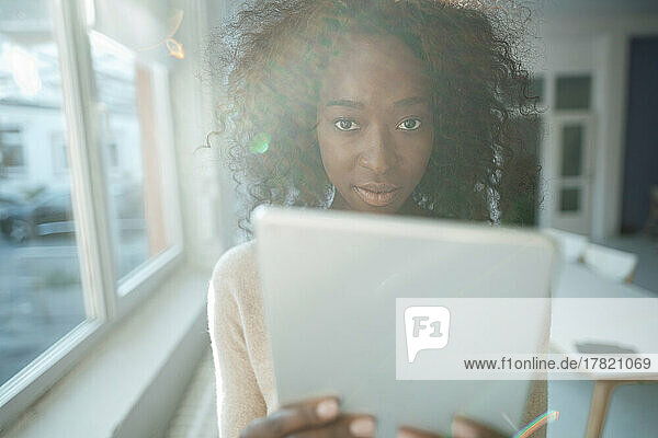 Young businesswoman with curly hair holding tablet PC in office