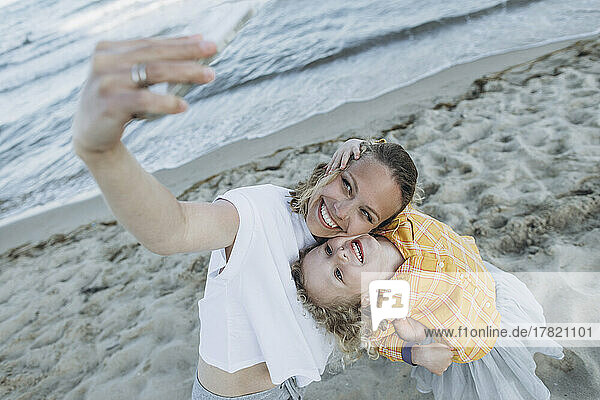 Glückliche Mutter mit Tochter  die am Strand ein Selfie mit dem Smartphone macht