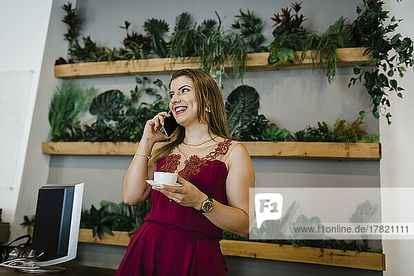 Smiling businesswoman talking on smart phone in green office