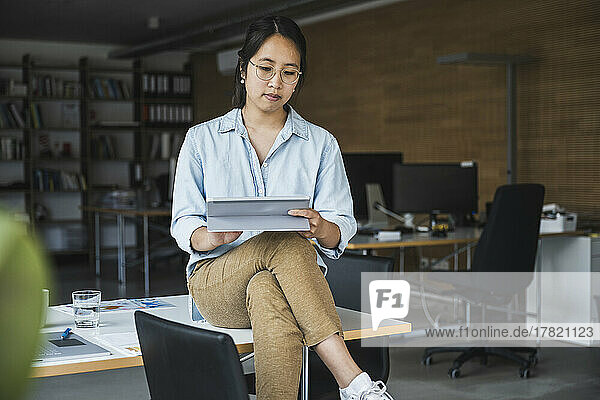 Geschäftsfrau sitzt am Schreibtisch im Büro und benutzt einen Tablet-PC