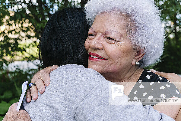 Smiling senior mother hugging daughter in park
