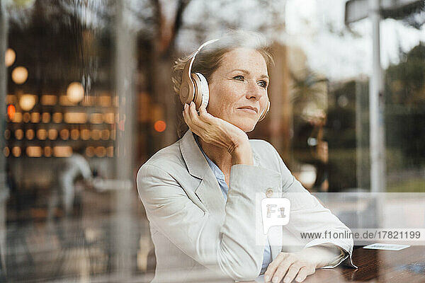 Businesswoman listening music through wireless headphones in cafe